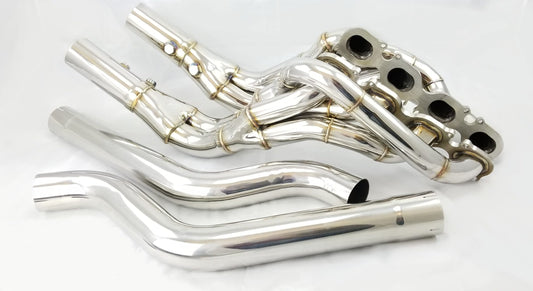 Close-up of T-304 stainless steel M156 long tube performance headers with midpipes, designed for Mercedes-Benz AMG vehicles, showcasing precision welds and direct-fit W204 chassis compatibility.