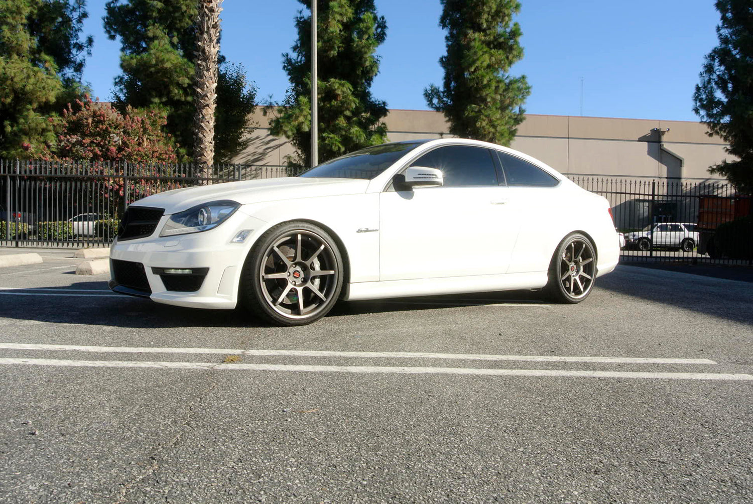 White Mercedes-Benz W204 C63 AMG coupe with Megan Racing 0.75 inch lowering springs installed, showing aggressive lowered stance