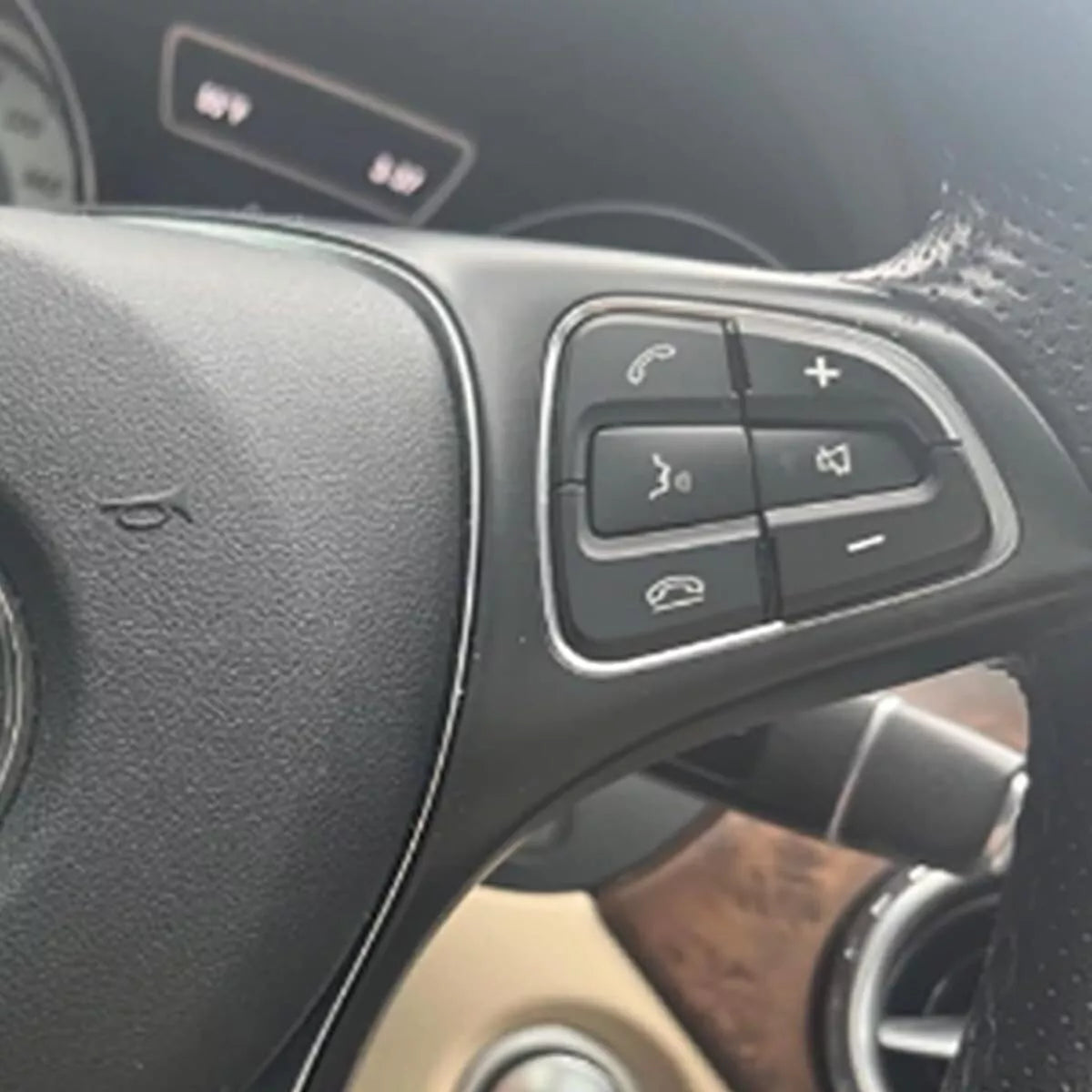 Molded black button overlays installed on a Mercedes multifunction steering wheel, front view