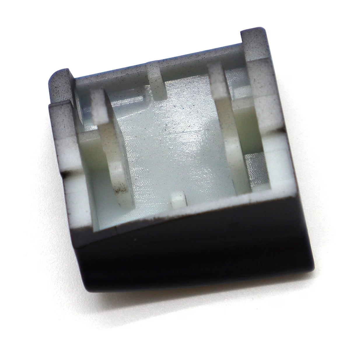 Underside of a black window switch button cap showing the clip cavity and locating tabs