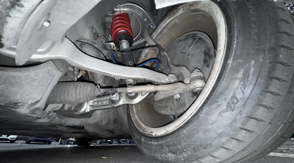 Suspension assembly and brake hose visible in wheel hub region.