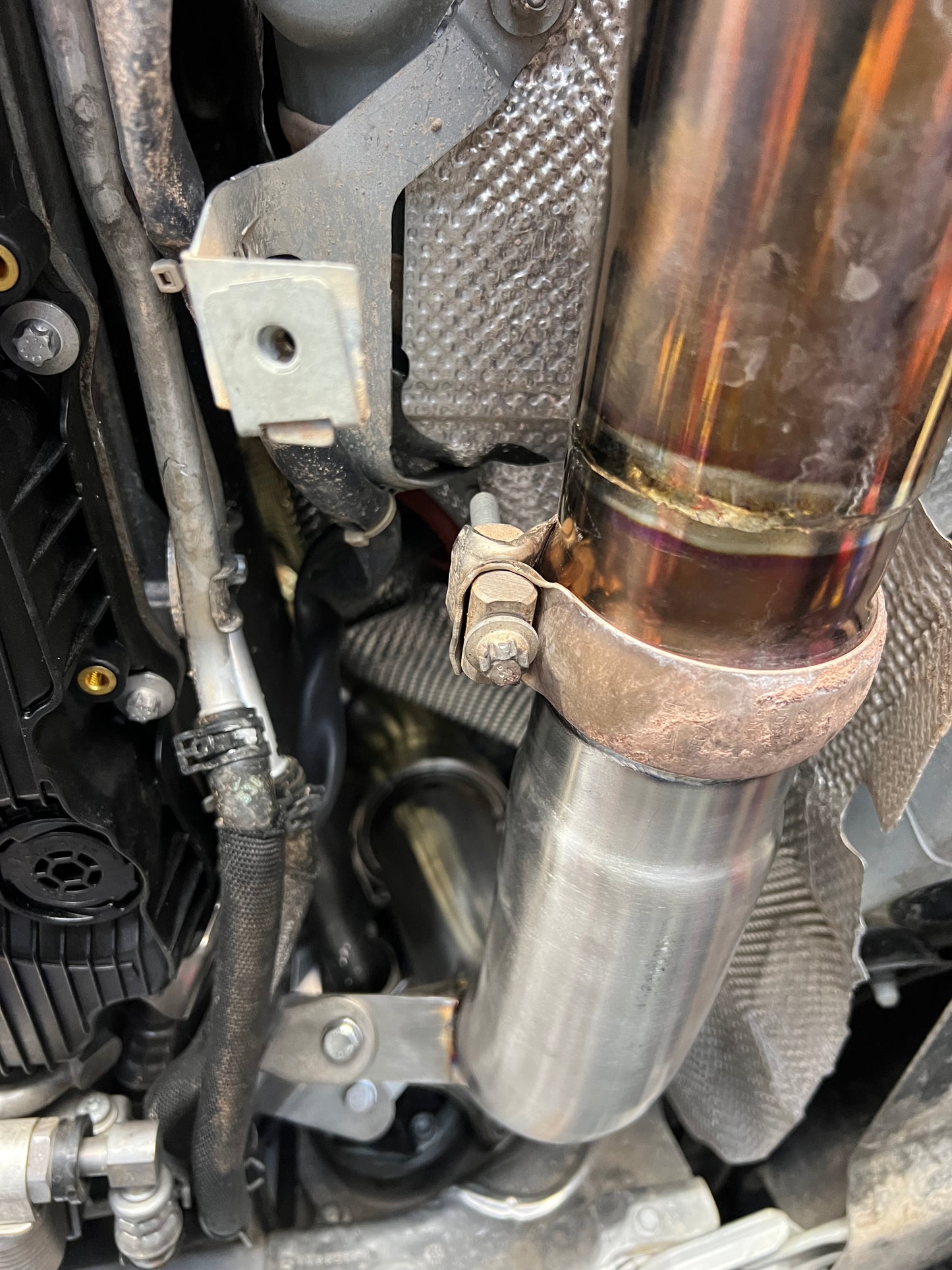 W213 E63 AMG mid-pipe section showing bracket support and V-band clamp connection